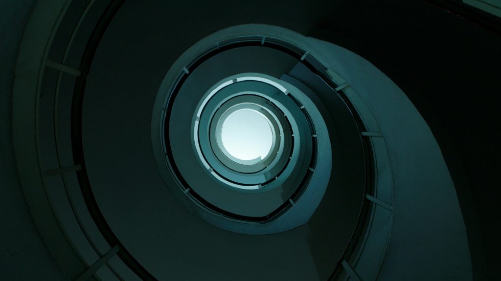 Artistic spiral staircase with modern architecture captured from below in dramatic lighting.