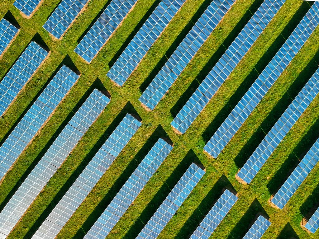 High-angle aerial shot of solar panels in a lush green field, located in Rockbeare, UK.